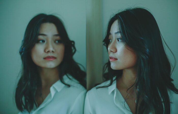 kendini sabote etmek, Aynaya bakan genç kadın, içsel farkındalık, öz şefkat, kendini sorgulama, kendini sabote etme, bilinçaltı farkındalık, kişisel gelişim görseli